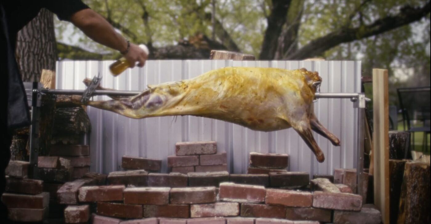 Whole lamb roasting on a spit over open fire